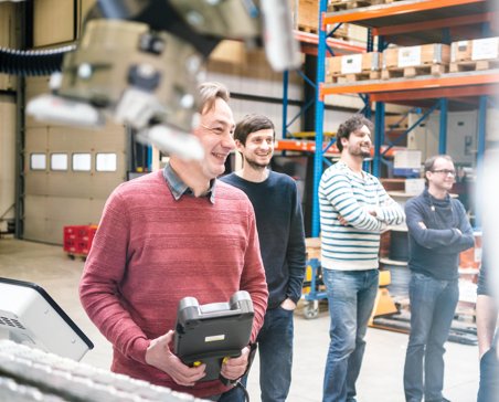 a cnc operator smiling while holding a teach pendant